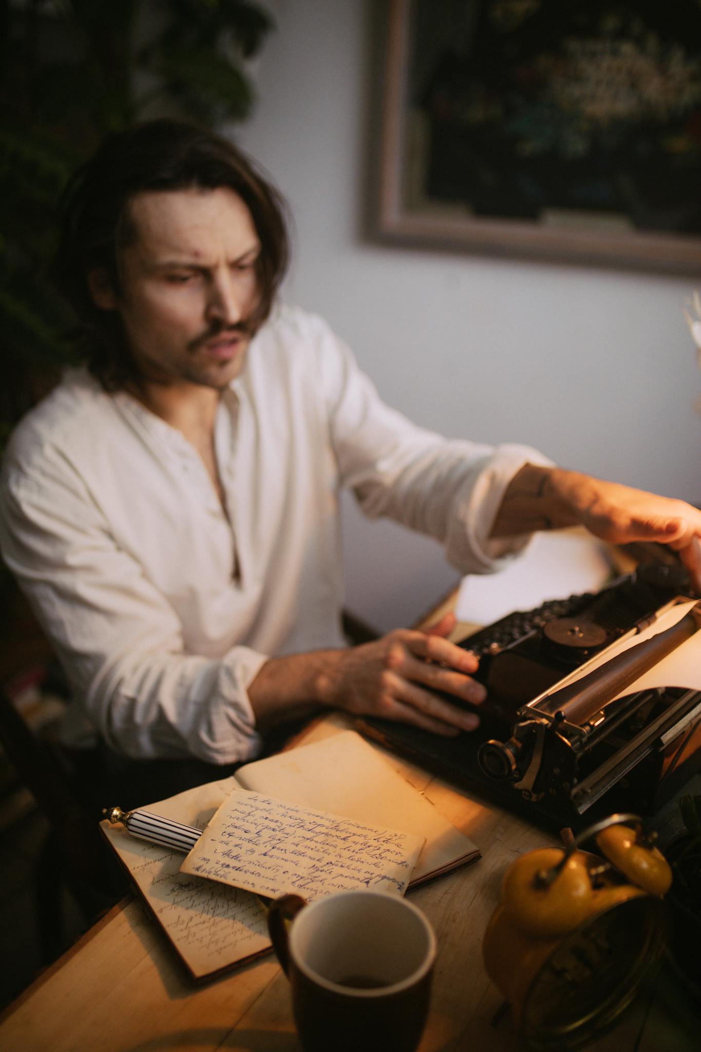 A writer focused on typing with a vintage typewriter at a wooden desk with a notebook.